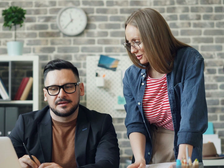 Two colleagues reviewing a laptop together at an office desk